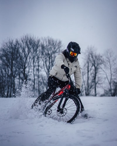 人在白色夹克骑在黑色山地车冰雪覆盖的地面白天
